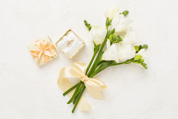 White fresia flower and gift box with diamond ring on concrete background, top view