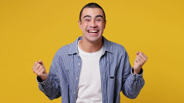 Young middle eastern man he wear blue shirt white t-shirt look camera surprised ask what wow omg no way doing winner gesture say yes celebrating put hands on face isolated on plain yellow background