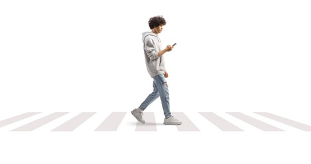 Young man wearing a gray hoodie and crossing a street with a smartphone