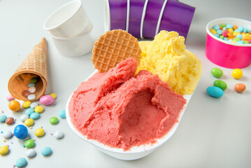  ice cream tubs in various fruit flavours with biscuits cones and sugared almonds on a white...
