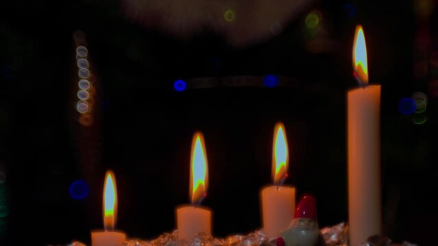 View of four burning candles in a traditional Advent candle holder as part of Christmas celebration against a blurred background. Sweden.