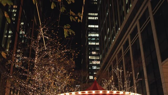 東京丸の内の並木道のクリスマスイルミネーションとメリーゴーランドと高層ビル群の夜景