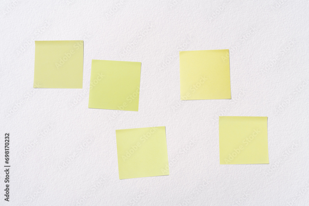 Poster five blank yellow post-it notes (sticky notes) on a white paper background. abstract background with