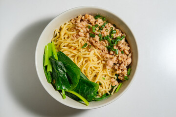 Bowl of chinese noodle with green mustard and minced soy chicken meat on white background