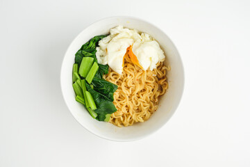 White ceramic bowl contains of instant noodle with vegetable and boiled egg inside with white background.