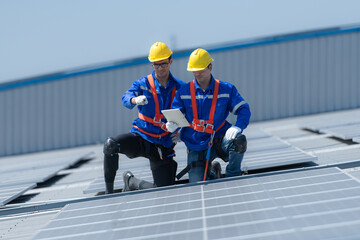 Both of technicians is installing solar panels on the roof of the warehouse to change solar energy into electrical energy for use in factories.