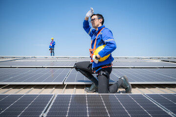 Technician repairing solar panels take off his hat and rest in the scorching sun on a factory roof...