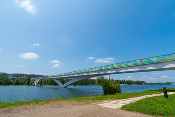 A view of the Mondego River in Coimbra, Portugal, under a clear sky, with trees and a pedestrian bridge. Landscape background and wallpaper.