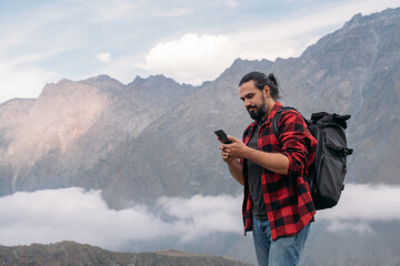 A male tourist with a large backpack and a phone in his hands.