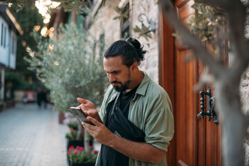 A confused male tourist with a phone in his hands on the street of the old town.