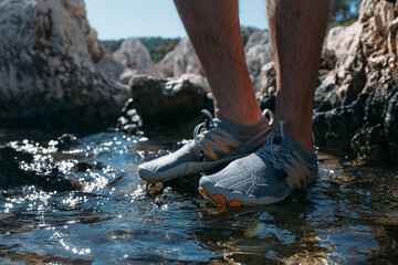 Protective swimming shoes on men's feet.  Close-up. Men's feet in stylish sports water slippers on...