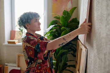 Proud girl hanging picture she drawn on wall in her studio