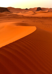 Sahara desert, orange dunes. Holidays and travel in Algeria, morning light over the desert. Rocks...