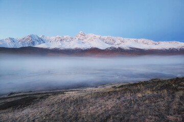 Beautiful nature scene in early autumn mountains. Foggy sunrise on the Dzhangyskol lake, Travel and winter vacation background.