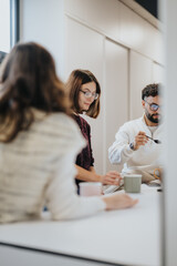 A group of young businesspeople enjoying a pleasant atmosphere in a modern kitchen. They are...