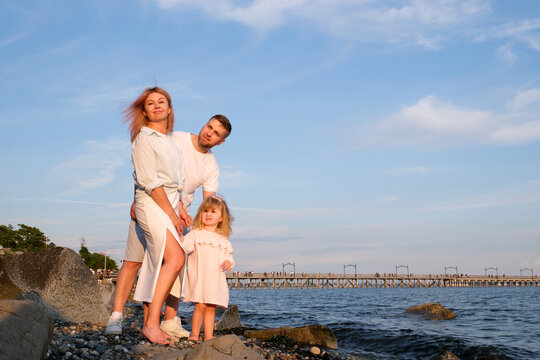 young happy family with the child at sunset at water look afar. High quality photo