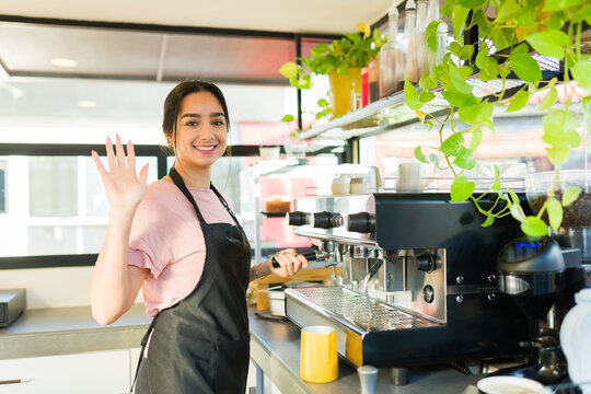 Young woman barista greeting customer in the coffee shop