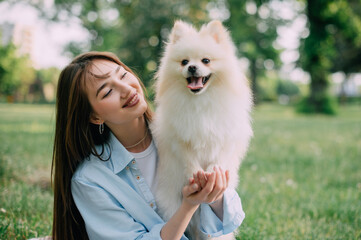 Portrait of a young woman with her dog. Pomeranian in the hands of his owner.