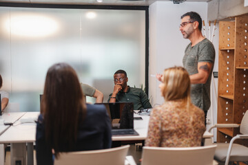 Businessman explaining new project to his multiracial employees during meeting at modern office