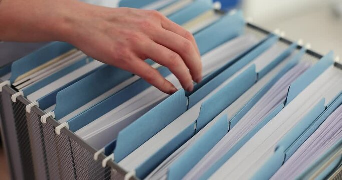 Female hands inserting blue folder into storage box in office closeup 4k movie slow motion
