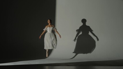 Portrait of female on white background in studio under spotlight. Beautiful ballerina in white...