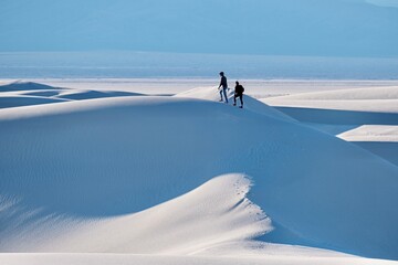 Two people walking on white sand dunes in distance. White  Sands National Park. Alamogordo. New Mexico. USA