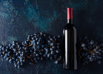Bottle of red wine and grapes on a blue vintage background.