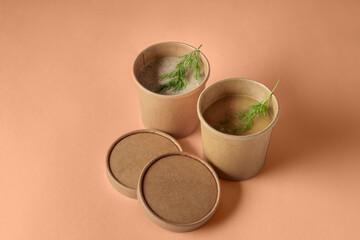 Trendy color of year 2024 - Peach Fuzz background. Pea and mushroom soup in paper disposable cups...