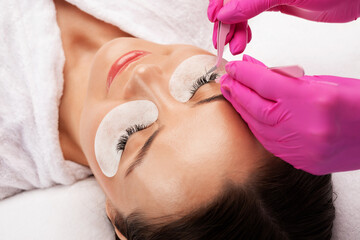 Obraz na płótnie Canvas Beautiful Woman with long eyelashes in a beauty salon. Eyelash extension procedure. Lashes close up