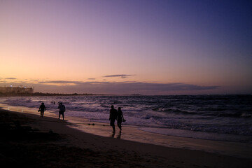 Silhouette de personnes marchant sur la plage le soir. - 698247285
