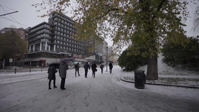 people walking with umbrelas on snowy roads in oslo in slow motion