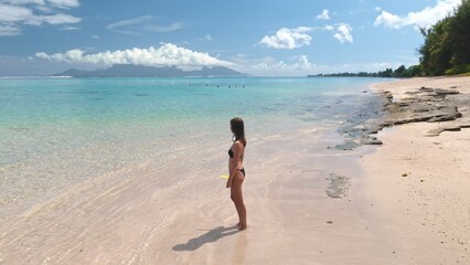 Girl in bikini standing on sand beach enjoy beautiful exotic nature landscape. Woman with snorkel...