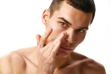 Obraz premium Portrait of handsome young man with brown short hair and spotless, clear face, taking care after skin against white studio background. Concept of male beauty, skin care, spa, cosmetology, men's health