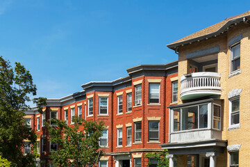 Classic style row houses in a summer day, featuring bay windows and red and yellow brick facades,...