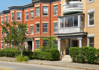 Classic style row houses in a summer day, featuring bay windows and red and yellow brick facades, Brookline, MA, USA