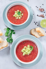 Cold soup Gazpacho garnished with cucumber and cilantro, in bowl, vertical top view