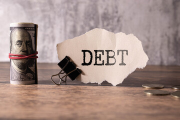Text Debt on white sheet with paper clips, magnifier, calculator and tables.