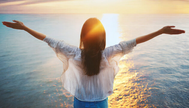 Silhouette of person by ocean at sunrise, arms outstretched, embracing freedom and joy of life