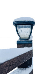 Isolated wood fence post leads to glass and metal light fixture. The snow cover is fresh with...