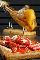 Slices of jamon serrano, jamon iberico, smoked sausage, ham or prosciutto crudo parma on wooden...