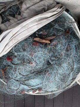 Used Fishing net with buoys, plastic floats  and ropes stored in a bag near boat. Fishing industry waste