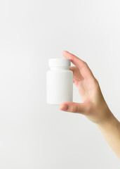 hand holding empty white plastic pill bottle