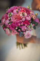  A stylish bride with a beautiful bouquet in her hands. Wedding bouquet for the bride and groom at an event. Wonderful luxury wedding bouquet of different pink flowers. Elegant wedding decorations.