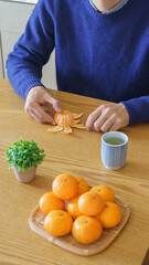 みかんの皮を剥く男性・日本のみかんと緑茶