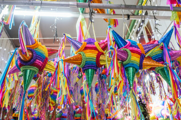 Colorful piñatas of different shapes and sizes hanging over the stalls of a traditional Mexican market.