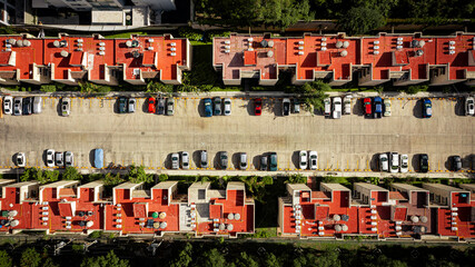 Drone top down shot of condominium with red roof tops and parking lots.