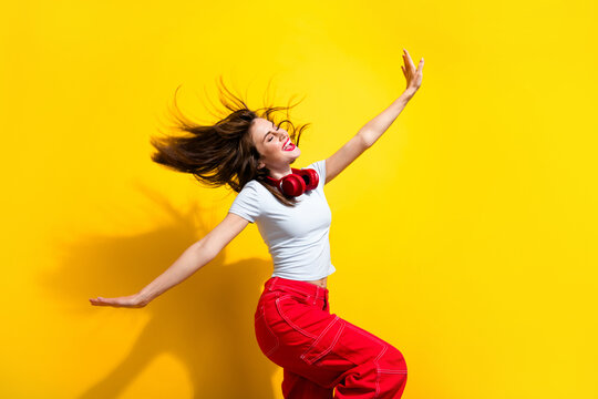 Photo of excited sweet woman dressed white t-shirt headphones flying hair dancing discotheque arms sides isolated yellow color background