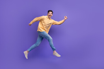 Fototapeta na wymiar Full body photo of nice young male running hurry fast excited dressed stylish yellow outfit isolated on purple color background