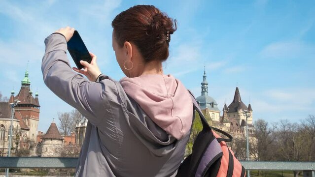 Photo from budapest trip. A view of pretty woman traveler with backpack takes a photo of famous buildings of Budapest during holidays.
