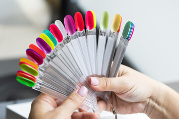 Collection of nails color polish samples. A palette of nail designs of different colors with gel polish. Transparent tips with nail polish samples. Demonstration fan-shaped palette of color shades. - obrazy, fototapety, plakaty